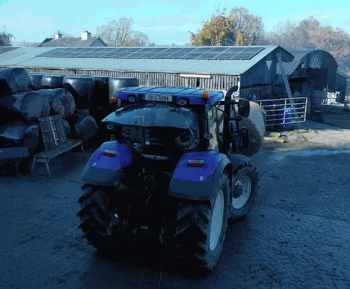 Blue Tractor with rooftop in the distance, agricultural solar panels in Ireland.